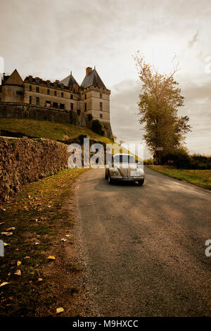 Un classique VW Coccinelle durs passé le château de Biron un château dans la vallée de la Lède sur la commune de Biron en Dordogne France. Banque D'Images