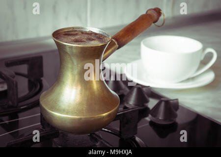 La cuisson du café sur une cuisinière à gaz. Ancien bain turc marmite en cuivre pour préparer le café sur la cuisinière dans la cuisine. Petit-déjeuner tôt. Méthode de préparation du café turc. Banque D'Images