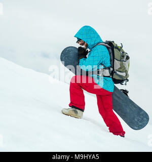 Jolie jeune femme en randonnée dans les montagnes de snowboard Banque D'Images