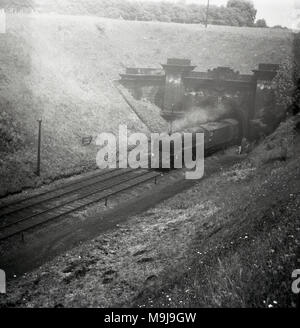 Années 1950, historique, d'une locomotive à vapeur sur une ligne de chemin de fer, qui sortent d'un tunnel, England, UK. Banque D'Images