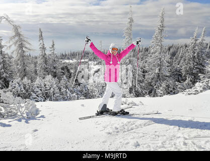 Jeune femme en rose veste de ski avec skis sur ses pieds tenant des bâtons de ski, à happy smiling posent au cours de l'hiver ensoleillé agréable journée. Ski Strbske Pleso resor Banque D'Images