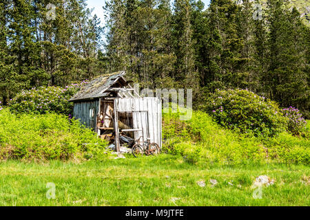 Hangar abandonné dans les Highlands écossais avec un vélo rouillé à l'extérieur. Banque D'Images