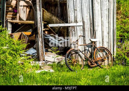 Hangar abandonné dans les Highlands écossais avec un vélo rouillé à l'extérieur. Banque D'Images