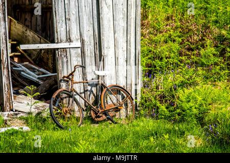 Hangar abandonné dans les Highlands écossais avec un vélo rouillé à l'extérieur. Banque D'Images