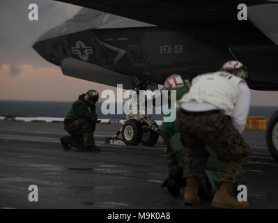 Les membres d'équipage affectés à l'Escadron d'avions de combat interarmées (VFA) 101 et l'USS ABRAHAM LINCOLN (CVN-72) ministère de l'aviation, se tenir près d'un F-35 Lightning II C, 17 mars 2018, dans l'océan Atlantique. Porte-avions au cours de la formation de qualification, les pilotes et les membres du personnel de pont exécutée plusieurs touch-et-va et d'atterrissage sur le pont du navire. (U.S. Photo de l'Armée de l'air par le sergent. Peter Thompson/libérés) Banque D'Images