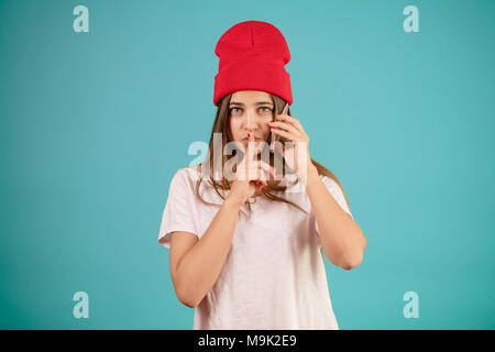 Jolie femme élégante avec téléphone mobile sur son oreille est debout avec le geste du silence garder des secrets. Banque D'Images