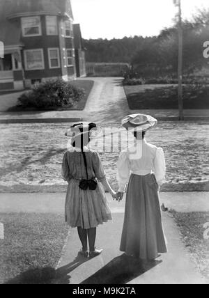 Deux femmes victoriennes visage et tenir la main, ca. 1900. Banque D'Images