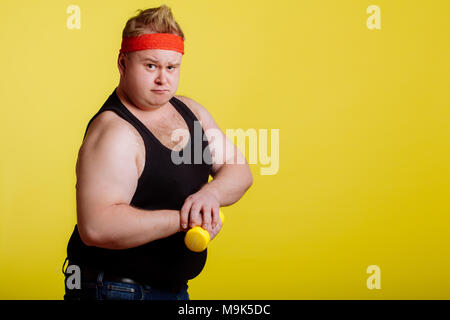 Fat Man montre ses muscles tout en maintenant l'haltère dans la main Banque D'Images