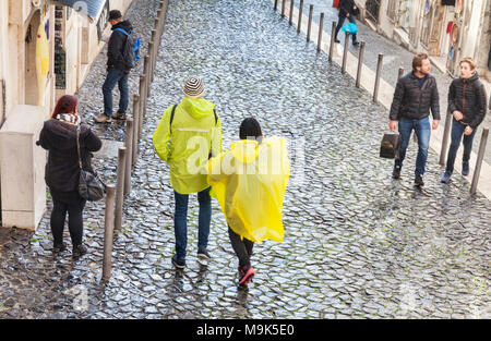 1 mars 2018 : Lisbonne Portugal - Couple portant des capes de pluie en plastique jaune dans la vieille ville de Lisbonne par temps humide. Banque D'Images