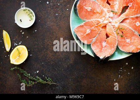 Le saumon frais et les ingrédients pour la cuisson (huile d'olive, citron, épices) sur une table en pierre. Une bonne nutrition. Banque D'Images