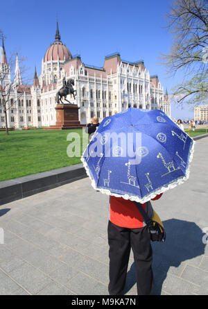 Femme avec un parasol bleu devant le parlement hongrois bâtiments dans la capitale de la Hongrie, Budapest accueil au gouvernement hongrois Banque D'Images