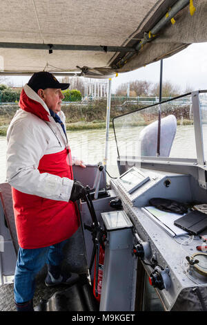 L'Angleterre, Sandwich. P22. Un homme âgé, skipper sur le bateau de la direction avec la roue du navire sur un pont ouvert. Close up. Banque D'Images