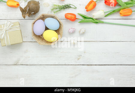 Vue de dessus de table Décoration de Joyeuses Pâques vacances concept fond.Télévision jeter bunny avec oeufs et fleurs tulipes poupée sur lapin en bois blanc moderne Banque D'Images