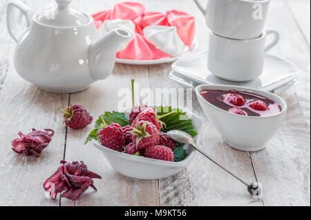 Un petit-déjeuner sain avec le muesli, de framboise et de fruits frais est servi sur une table en bois. Confiture de framboises avec du thé et de l'hibiscus séchées. Banque D'Images