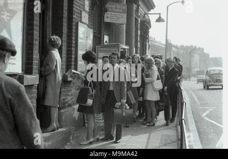 Années 1970, historiques, les passagers ferroviaires la queue sur le trottoir devant la gare la nouvelle Croix du Sud-Est de Londres, en Angleterre. À ce moment, les grèves et les trains étaient annulés une occurrence commune sur British Rail et dans ce cas, les plates-formes ont été trop plein pour prendre plus de passagers. Banque D'Images