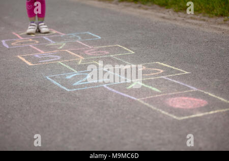 Fille jouant hop-scotch en aire de jeux Banque D'Images