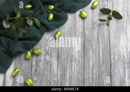 Les œufs en chocolat de Pâques en aluminium avec tissu vert gris sur fond de bois Banque D'Images