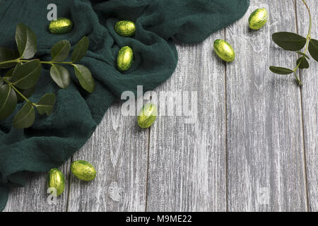 Les œufs en chocolat de Pâques en aluminium avec tissu vert gris sur fond de bois Banque D'Images