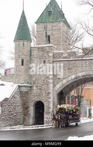 Excursion à cheval de la ville de Québec dans la neige : une équipe de chevaux tire un chariot à roues décorées sur la rue à travers la porte Saint-Louis dans les murs de la ville. Banque D'Images