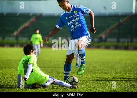 Un enfant lance une vitre coulissante s'attaquer sur des profils joueur pendant un match amical pour célébrer le 85e anniversaire de Persib Bandung, Indonésie en FC. Banque D'Images