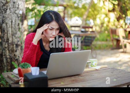 Worried woman using laptop et boire du café dans le jardin Banque D'Images