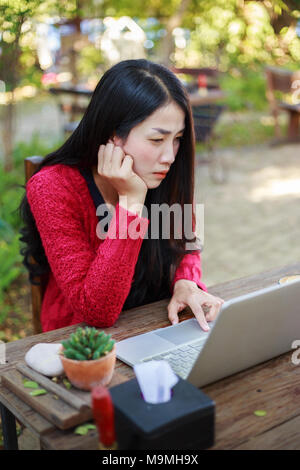 Young woman using laptop et boire du café dans le jardin Banque D'Images