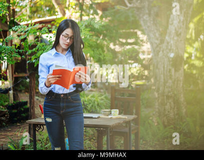 Portrait femme lisant un livre dans le jardin Banque D'Images