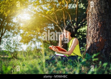 Jeune femme en situation de stress lors de la lecture d'un livre dans le parc Banque D'Images