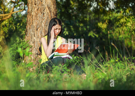 Jeune femme en situation de stress lors de la lecture d'un livre dans le parc Banque D'Images