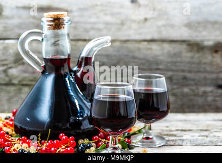 Liqueur de fruit dans une bouteille et verre de l'alcool doux sur table en bois Banque D'Images