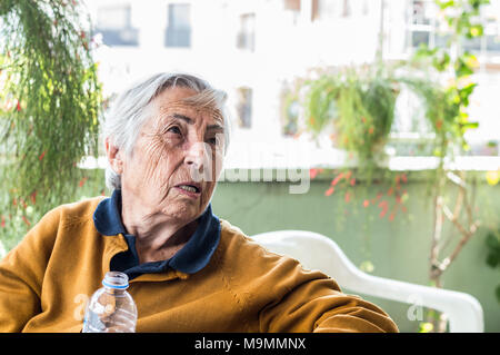 Vieille Femme assis sur le balcon en train de discuter avec sa famille. Banque D'Images