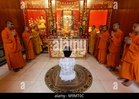 Cérémonie de sacrifice bouddhiste avec la prière des moines et des femme agenouillée, Wat Mangkon Kamalawat, temple bouddhiste chinois, Chinatown Banque D'Images