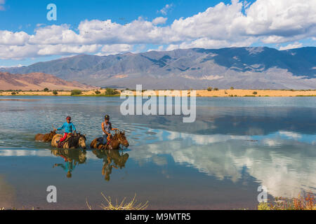 Les enfants nomades sur des chevaux qui traversent la rivière Tuul au cours de l'été, le Parc National de Gorkhi-Terelj, Mongolie Banque D'Images