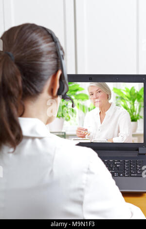 Femme médecin de la gériatrie avec casque en face de son ordinateur portable pendant un appel vidéo avec une vieille patiente sur son médicaments prescrits, la santé numérique Banque D'Images