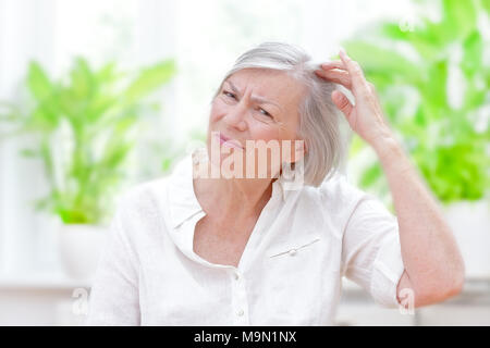 Impatient woman dans sa salle de séjour ou un bureau de médecins lui montrant l'amincissement des cheveux ou la perte de cheveux Banque D'Images