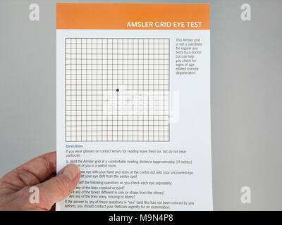 Personne âgée Senior hand holding et à la grille d'Amsler à un examen de la vue carte pour vérifier la vue pour la dégénérescence maculaire liée à l'âge dans les yeux. UK Banque D'Images