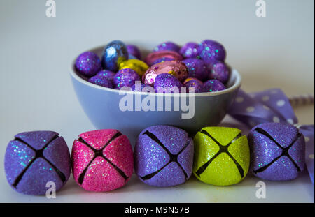 Oeufs de Pâques colorés chocolats et bonbons dans un bol bleu et décorations Banque D'Images