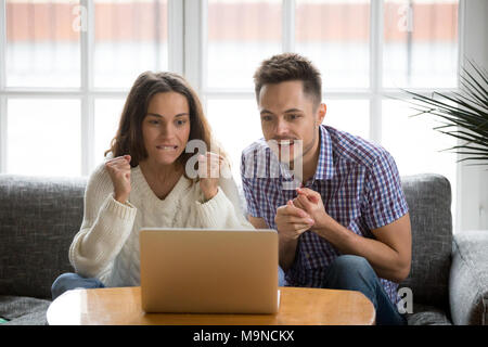 Couple excité nerveux en tension work à la recherche à l'écran de l'ordinateur portable, l'homme et la femme football fans acclamer l'équipe de soutien du sport regarder champi Banque D'Images
