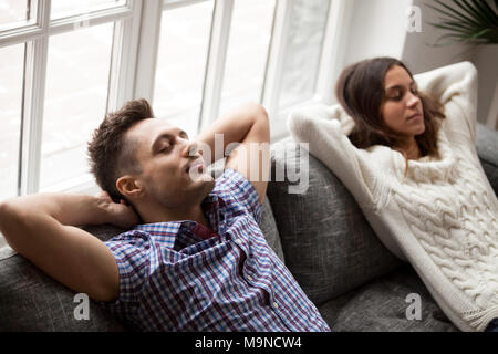 Young couple relaxing on sofa holding hands behind head, détendu l'homme et la femme se reposant sur la table à la maison ensemble, heureux de prendre la famille brea Banque D'Images