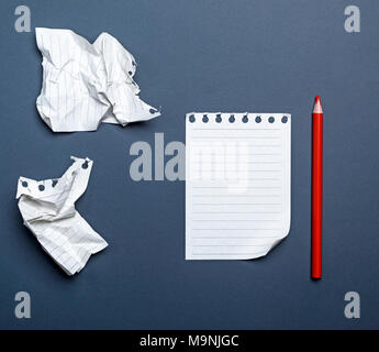 White feuilles vierges dans une ligne d'un bloc-notes et crayon de bois rouge sur fond noir, vue du dessus Banque D'Images