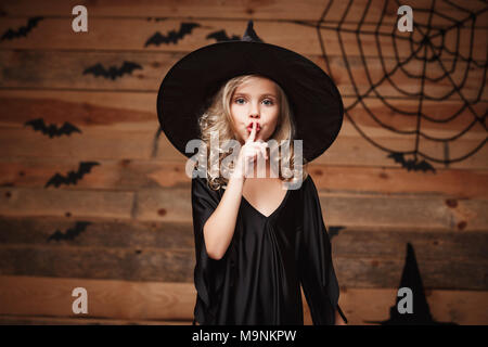 Sorcière Halloween concept - photo de gros plan peu sorcière caucasien enfant tenant l'index à lèvres, lui demandant de garder le silence. Banque D'Images