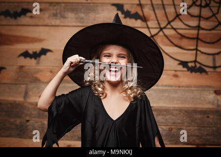 Sorcière Halloween concept - petite sorcière enfant jouer avec baguette magique. plus de chauve-souris et araignée arrière-plan. Banque D'Images