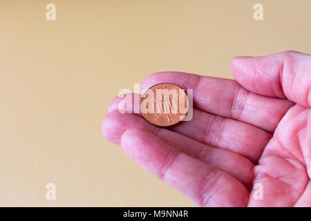 Une main de femme tenant un pence sterling britannique (Penny) coin, Royaume-Uni Banque D'Images
