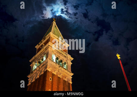 Le Campanile de la Place St Marc à Venise vu la nuit avec de l'or rouge, mât incliné clocher illuminé et toit pyramidal atteignant pour la lune Banque D'Images