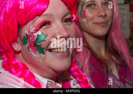 Femme en perruque rose avec Holly peint sur son visage lors d'une foire de Noël Banque D'Images
