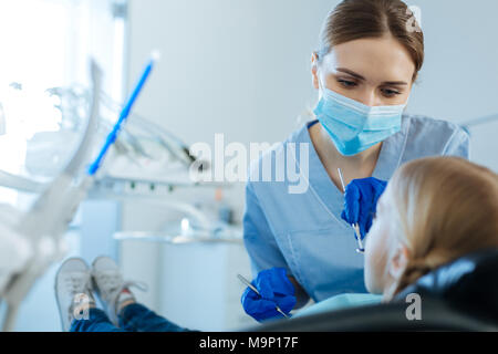 Femme agréable dentiste contrôle de la cavité buccale avec miroir spécial Banque D'Images