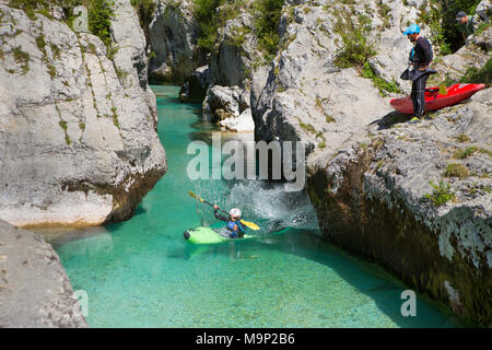 Un homme dans un kayak est de sauter dans l'eau, tandis qu'un autre homme regarde. L'émeraude Soca près de Bovec en Slovénie, originaires de la Triglav, est célèbre pour tous les types d'activités d'eau vive. Banque D'Images