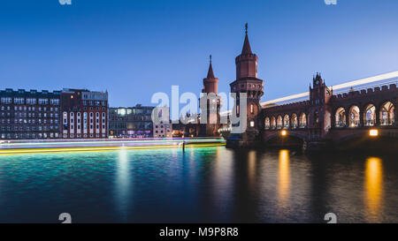 Berlin Oberbaum Bridge avec traces de lumière du bateau et train le soir, Berlin, Allemagne Banque D'Images