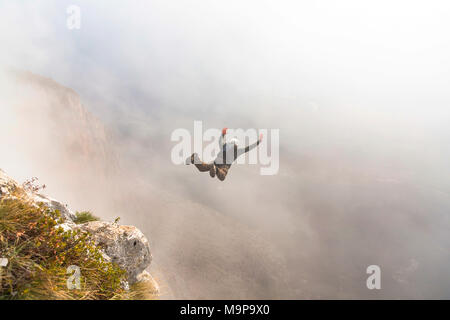 Cavalier Base mid air juste après cliff jump pendant temps de brouillard, Brento, Vénétie, Italie Banque D'Images