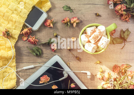 Tasse de café avec de la guimauve, laine à tricoter, blanc fleurs roses séchées, un téléphone mobile et d'écouteurs. Belle femme romantique. Shallow Banque D'Images